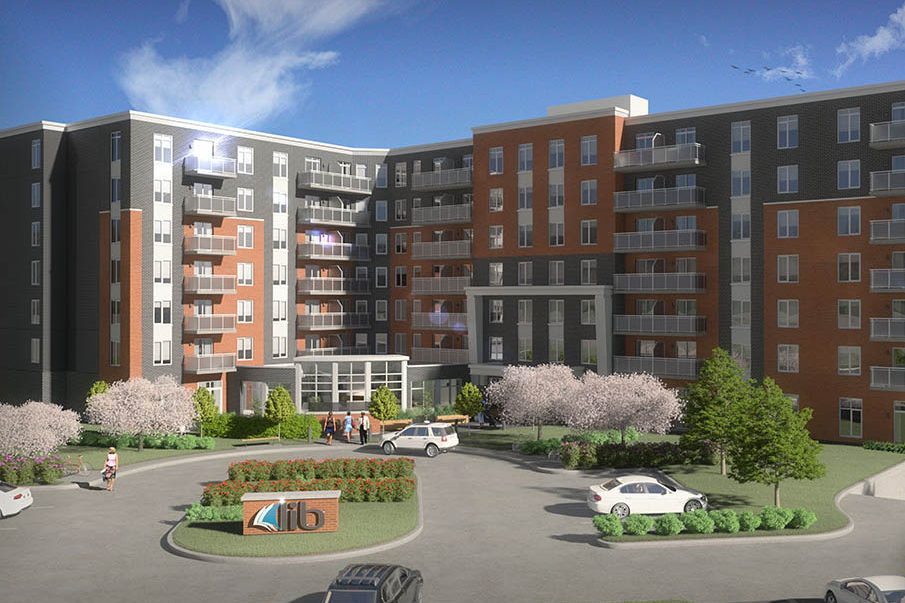Rendu de l’immeuble Lib Boisbriand : huit étages, brique rouge et panneaux gris, stationnement devant