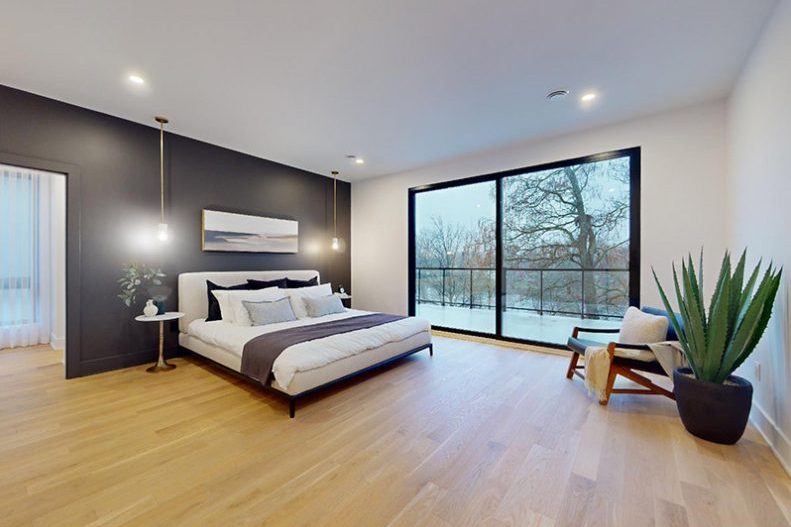 La chambre principale de la maison modèle : mur anthracite, lit bas, fenêtre sur les arbres