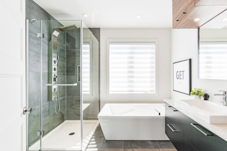La salle de bain : douche vitrée, baignoire autoportante, vanité noire