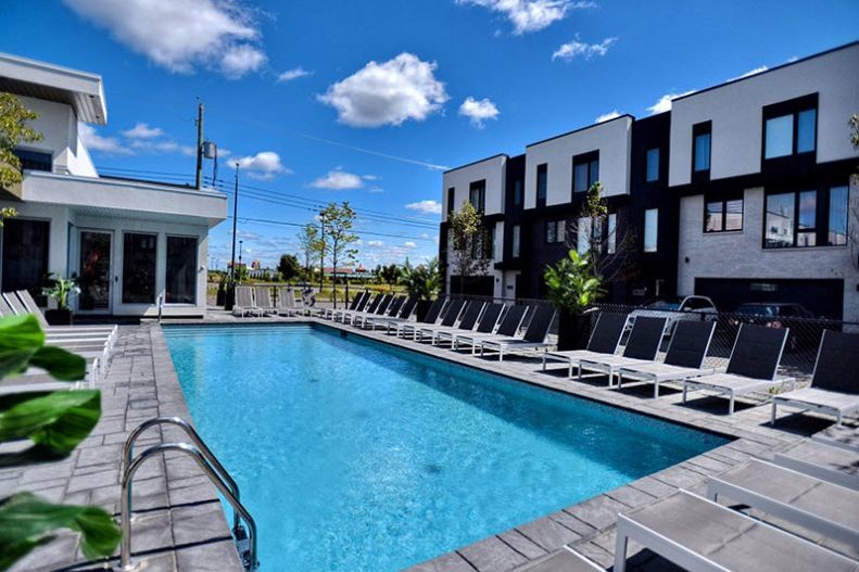 La piscine extérieure du pavillon central, chaises longues alignées, maisons de ville derrière