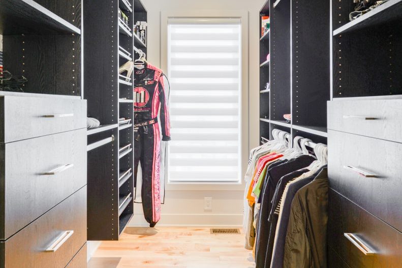 Le walk-in d’une chambre : tiroirs gris, tringles, fenêtre à store